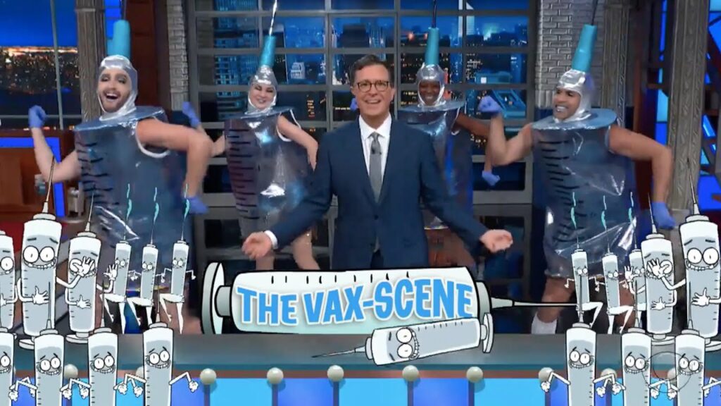 Screenshot from The Colbert Show showing Colbert dancing with extras who are dressed as syringes the promotion of in an effort to promote the Frankenshot.