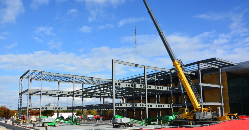 Structural steel frame under construction with crane erecting steel.