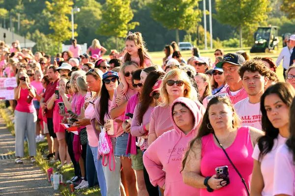 Mostly women, dressed in pink, line up next to the roadway to show their support for Lindsay Clancy