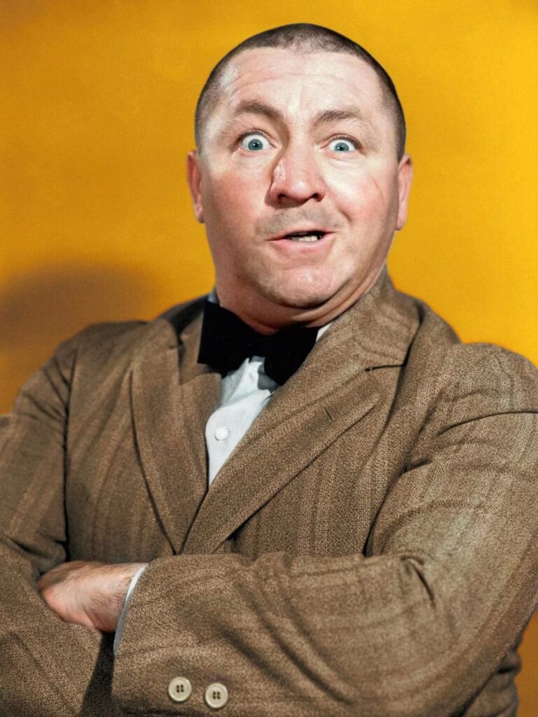 Colorized portrait of Curly Howard with arms crossed and a wide-eyed expression.